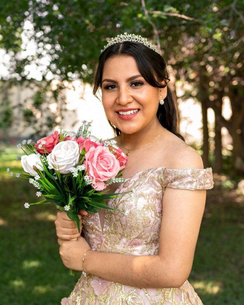 Beautiful woman in an elegant gown holding a bouquet of roses outdoors in Mérida, Mexico garden.